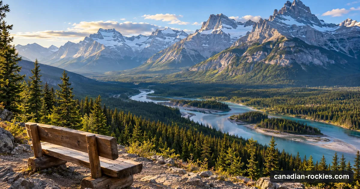 A trail viewpoint over a valley with a winding river below rugged grey peaks