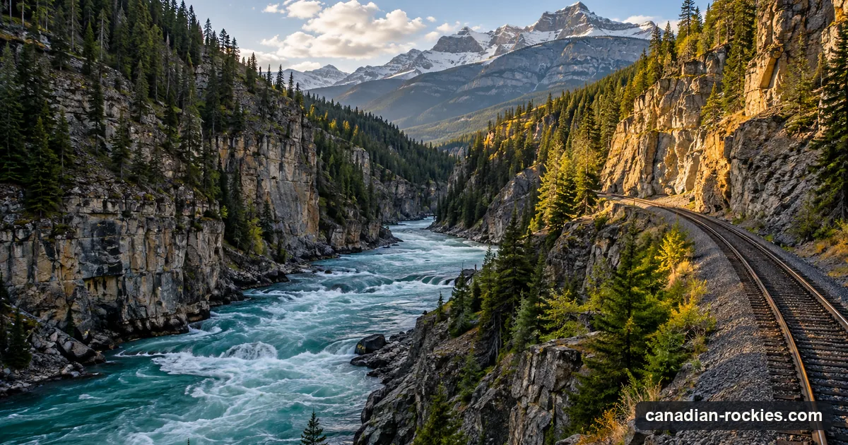 A railway line beside a green river in a deep forested mountain canyon